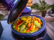 Comment préparer un tajine de poulet aux olives et citrons : une recette emblématique des cuisines maghrébines Scène de cuisine avec un tajine de poulet aux olives et citrons confits en cours de préparation