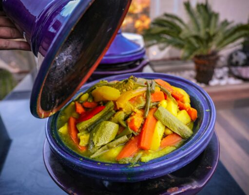Comment préparer un tajine de poulet aux olives et citrons : une recette emblématique des cuisines maghrébines Scène de cuisine avec un tajine de poulet aux olives et citrons confits en cours de préparation
