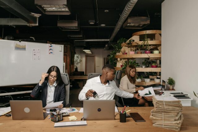 Businesswoman shaking hands with Moroccan man in a bustling office setting