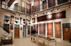 La valorisation des collections publiques de tapis marocains sous le protectorat français (1912-1935) Historian examining a vibrant Moroccan rug under a museum spotlight