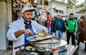 La street-food tunisienne fait ses preuves à la baraque : Découvrez les 5 plats incontournables Tunisian street food vendors serving delicious dishes to a happy crowd