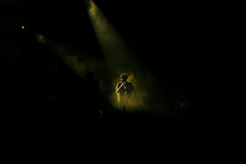 Sid Ali Driss en concert avec une foule enthousiaste derrière lui, en tenue de musique chaâbi.