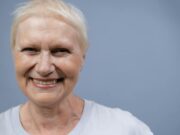 Cheveux gris et cancer : une théorie à découvrir Femme âgée aux cheveux gris regardant son reflet dans un miroir