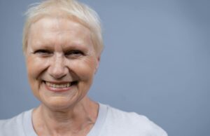 Cheveux gris et cancer : une théorie à découvrir Femme âgée aux cheveux gris regardant son reflet dans un miroir