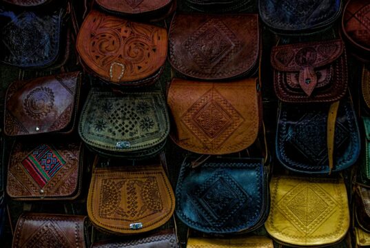 Le sac Talel Paris : fusion de mode et art au Maghreb Une femme portant un sac Talel Paris au Maghreb, avec des mosaïques romaines dans le fond