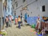 Chefchaouen: la nouvelle capitale de la mode marocaine explorée Woman wearing blue Chefchaouen attire walking in a bustling market street