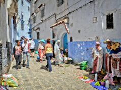 Chefchaouen: la nouvelle capitale de la mode marocaine explorée Woman wearing blue Chefchaouen attire walking in a bustling market street