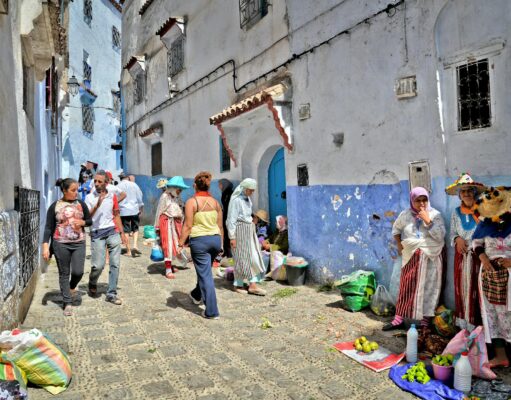 Chefchaouen: la nouvelle capitale de la mode marocaine explorée Woman wearing blue Chefchaouen attire walking in a bustling market street