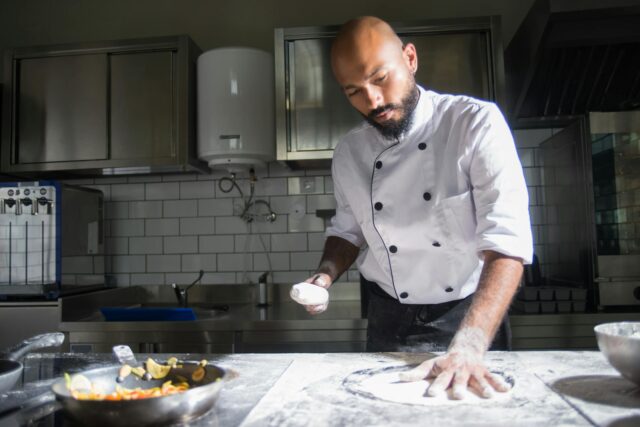 Algerian chef Mohamed Cheikh holding Top Chef trophy in front of traditional Algerian food spread