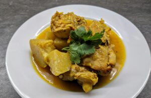 Le ragoût marocain aux patates douces et poulet : la recette parfaite pour utiliser les restes dans le frigo A bowl of Moroccan sweet potato and chicken stew with steamed rice, garnished with fresh coriander and a side of pita bread.