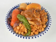 Recette traditionnelle tunisienne : Couscous au poulet et safran Tunisian chicken saffron couscous on a colorful tablecloth with steaming bowls and lemon wedges