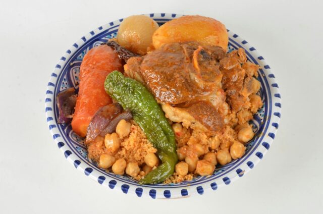 Famille algérienne mangeant des cocas aux poivrons verts et rouges sur une table à l'extérieur