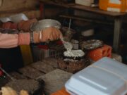 Cocas algériennes traditionnelles : une recette simple et croustillante pour le plaisir des palais Algérien familier en train de préparer des cocas traditionnelles sur une plage de sable au Maghreb