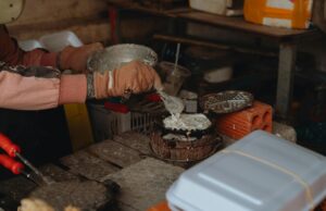 Cocas algériennes traditionnelles : une recette simple et croustillante pour le plaisir des palais Algérien familier en train de préparer des cocas traditionnelles sur une plage de sable au Maghreb