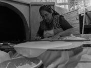 Tout ce que vous devez savoir sur les msemen : techniques et recettes woman preparing Tunisian Msemen with a rolling pin and ingredients on a countertop