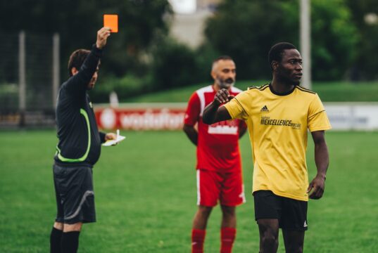 Fier de sa double culture : Ayyoub Bouaddi partage sa fierté après avoir été sélectionné avec l’équipe du Maroc pour la Coupe du monde 2026 Ayyoub Bouaddi en tenue nationale marocaine avec ballon de football derrière lui, souriant devant une arrière-plan de stade.