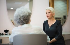 Cheveux Gris : Un Signal Anticancer ? Femme avec cheveux gris assise devant un miroir d'étude