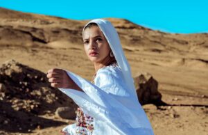 Samira Haddouchi : un hommage à la grande figure de la mode marocaine Samira Haddouchi wearing traditional Moroccan attire, posing in a Moroccan-style setting
