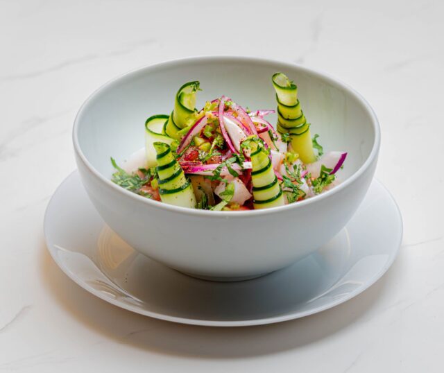 salade printemps marocaine apéro Salade du Printemps Marocaine avec avocat, tomates et olives sur une assiette de verre à côté d'un plafond marocain