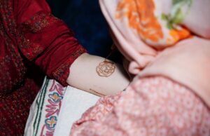Le henné maghrébin : une pratique culturelle pour la beauté et le bien-être woman applying henna to her hands in a traditional Moroccan setting