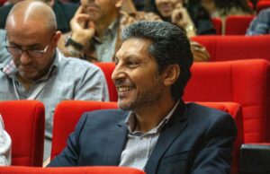 Hicham Lasri au FIRN de Frontignan : l’électron libre du Maroc partage son expérience Hicham Lasri donnant une conférence à FIRN de Frontignan avec un fond bleu et noir représentant les électrons libres