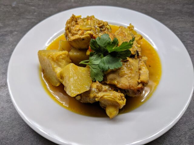 Moroccan chicken stew dish Moroccan chicken and sweet potato stew served in a large, colorful tagine with steamed vegetables on the side