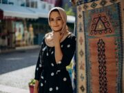 La mode contemporaine pour femme maghrébine : entre tradition et style moderne Femme maghrébine portant un hijab moderne et une robe traditionnelle au milieu d'un marché de textiles