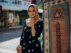 La mode contemporaine pour femme maghrébine : entre tradition et style moderne Femme maghrébine portant un hijab moderne et une robe traditionnelle au milieu d'un marché de textiles