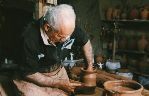 UNESCO célèbre l’excellence de l’artisanat tunisien : découvrez les maîtres artisans et leur héritage Tunisian potter working at his wheel with finished pottery on table