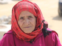 Environnement au Maghreb: Les oasis, les oubliées du développement durable Woman standing next to a palm tree oasis in the Maghreb, representing the forgotten regions crucial for sustainable developme