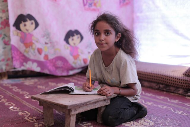 Enfant maghrébin assis à une table de devoir avec des livres