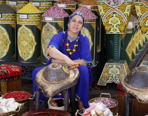 La mode marocaine s’ouvre à l’Asie : voyage de Marrakech à Kuala Lumpur Woman wearing traditional Moroccan fashion in Marrakech market, holding Asian fashion items