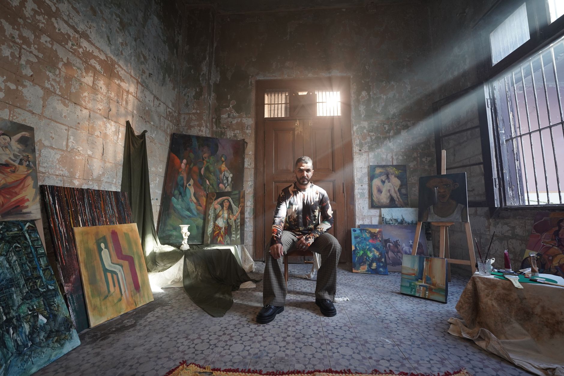 Taoufik Behi working on a painting in his studio, exploring social, political, and economic issues in modern Tunisia