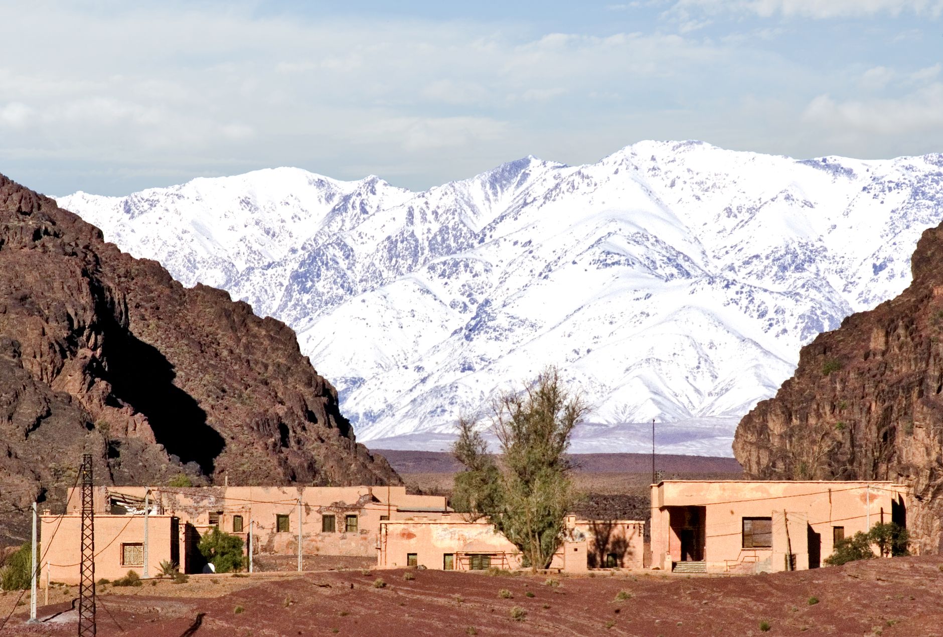 Famille marocaine dans un jardin enneigé, regardant un spectaculaire paysage avec montagnes à l'arrière-plan